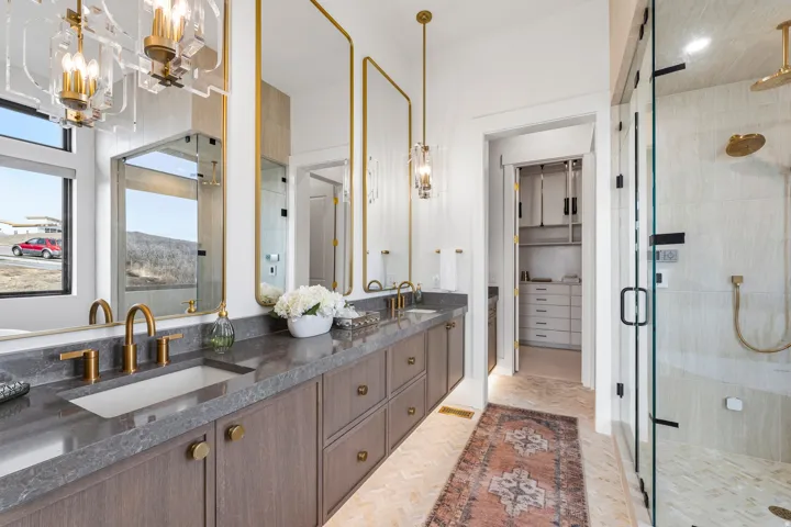 Full bathroom with double vanity, a shower stall, a chandelier, and a spacious closet
