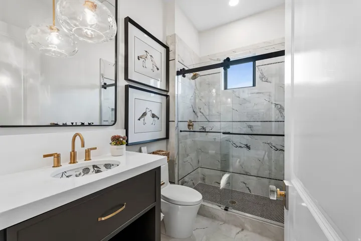 Full bathroom with vanity, a marble finish shower, and light marble finish floors