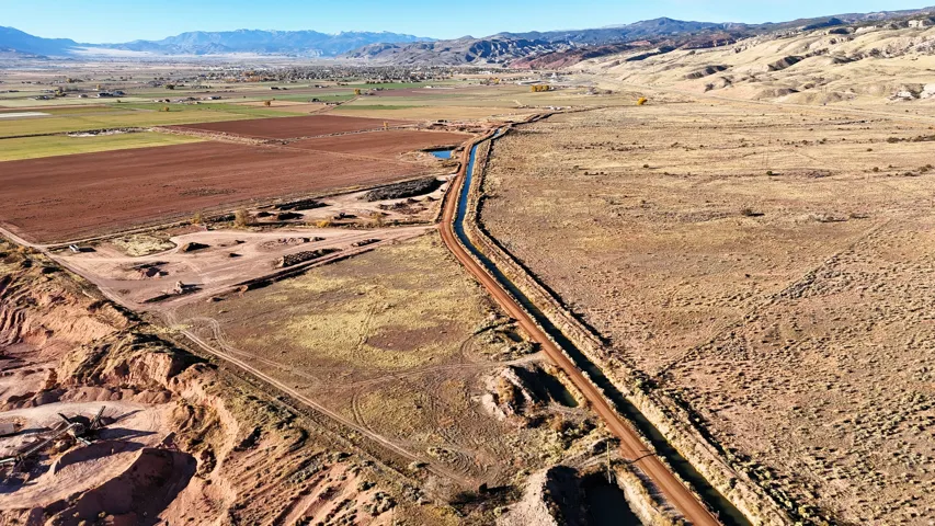 Expansive land parcel featuring varied topography, distant mountain ranges, and cultivated fields