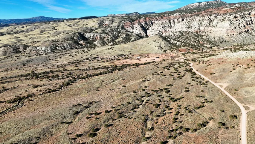 Expansive desert landscape featuring a dirt road, sparse vegetation, and distant mountains
