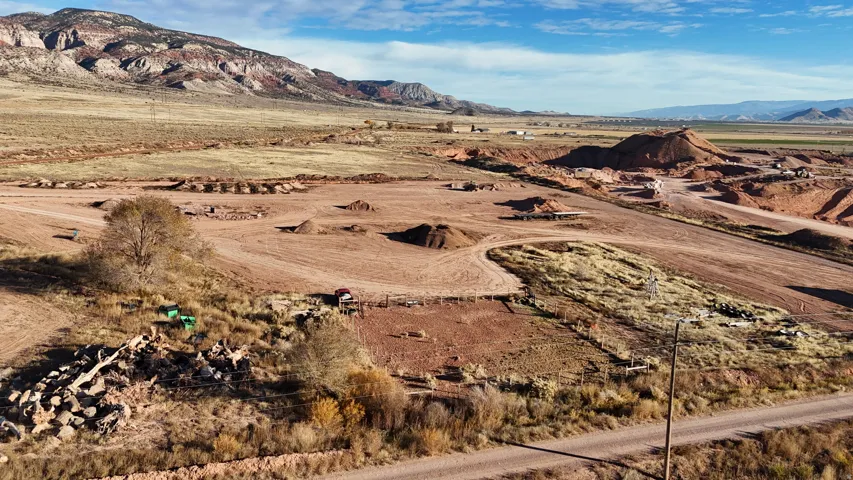 Expansive undeveloped land with a dirt road, natural vegetation, and distant mountain backdrops