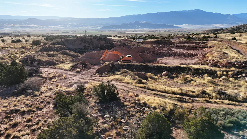 Expansive undeveloped land with excavated areas and distant mountains