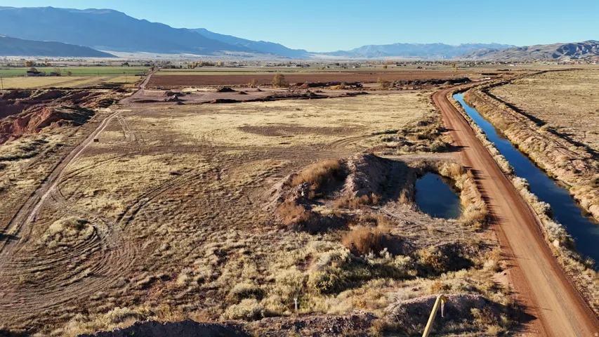 Expansive open land featuring a dirt road, irrigation canal, and distant mountains