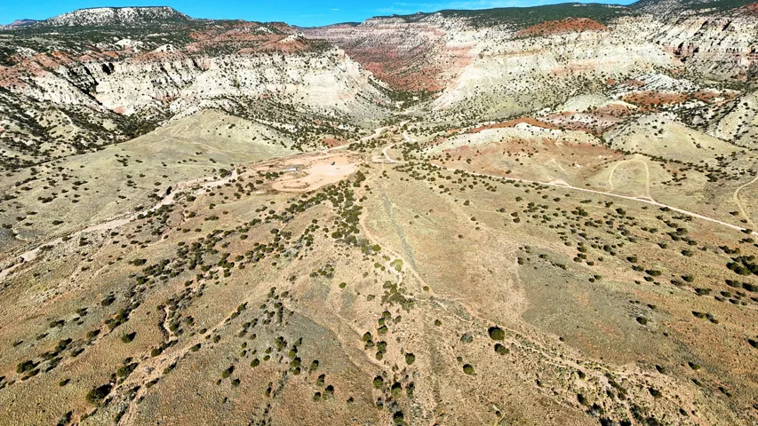 Expansive terrain featuring natural ground cover, elevated plateaus, and visible unpaved paths
