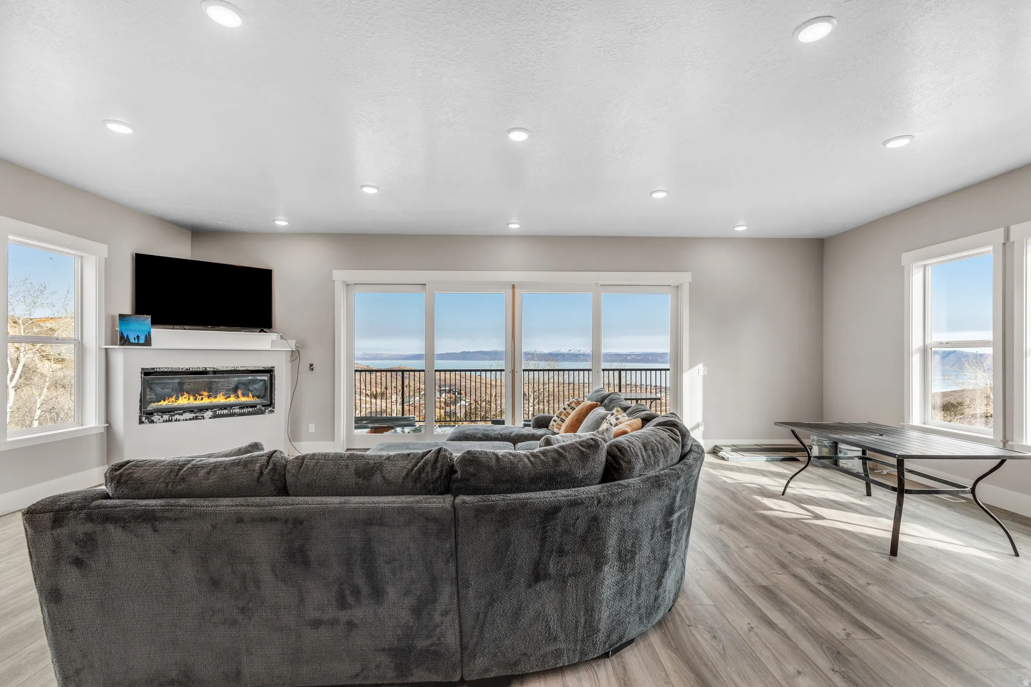 Living area featuring a glass covered fireplace, light wood-style floors, a textured ceiling, and recessed lighting