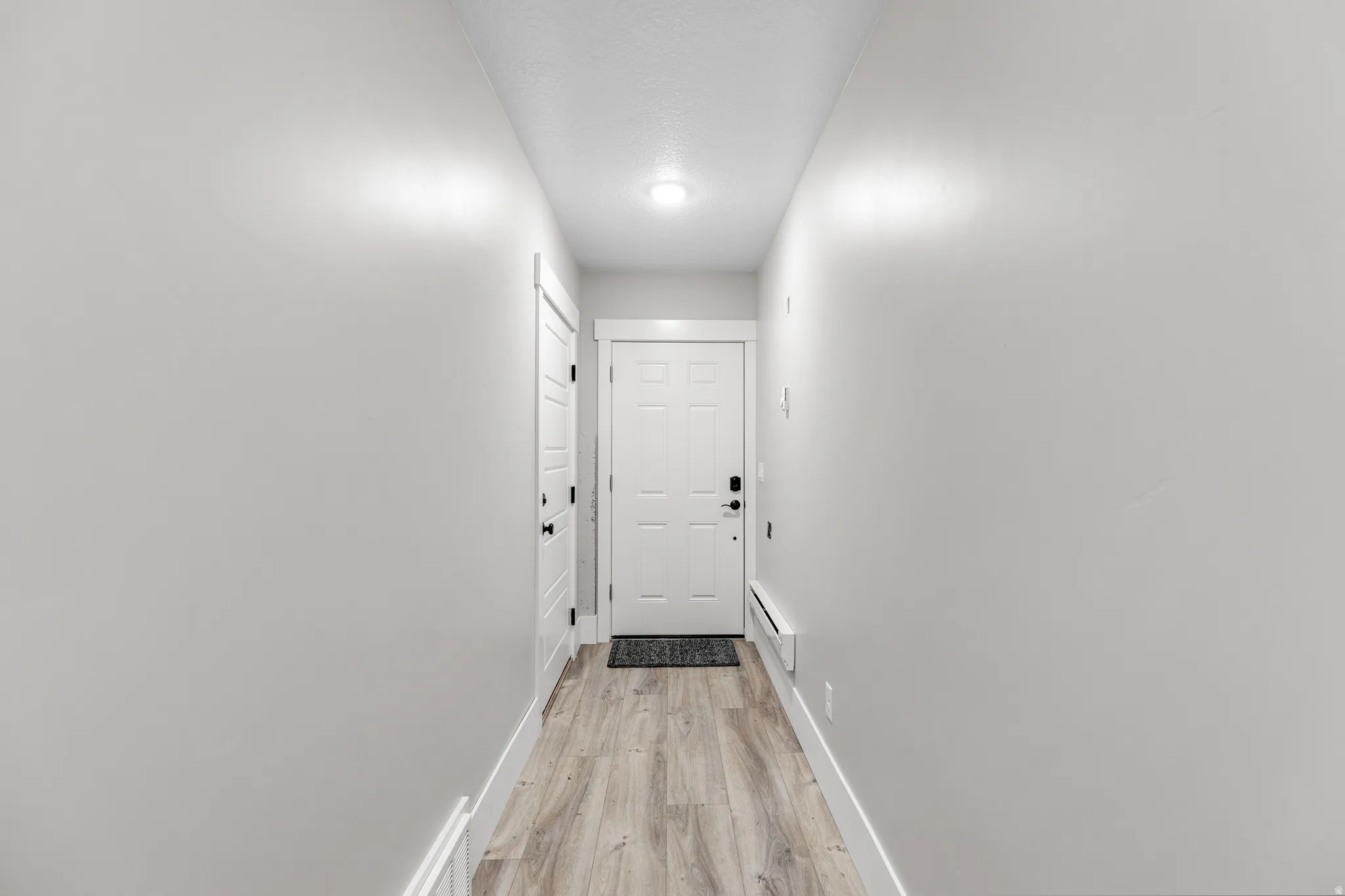 Corridor with light wood-style floors and baseboard heating