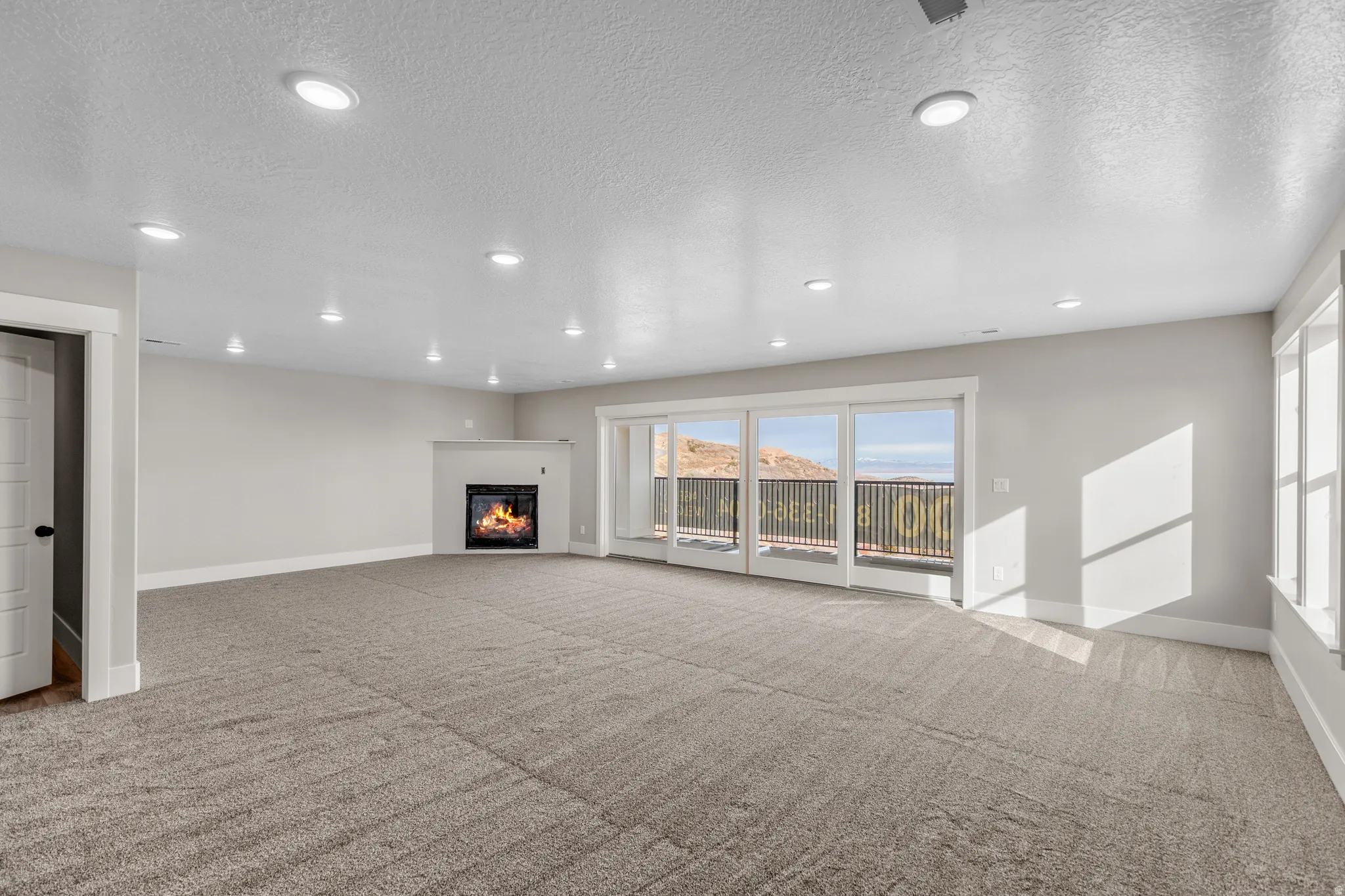 Unfurnished living room with recessed lighting, a textured ceiling, a glass covered fireplace, and light colored carpet