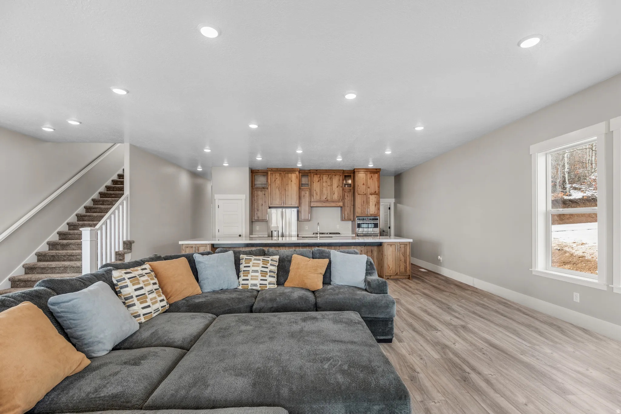 Living area with light wood-style flooring, healthy amount of natural light, recessed lighting, and stairs