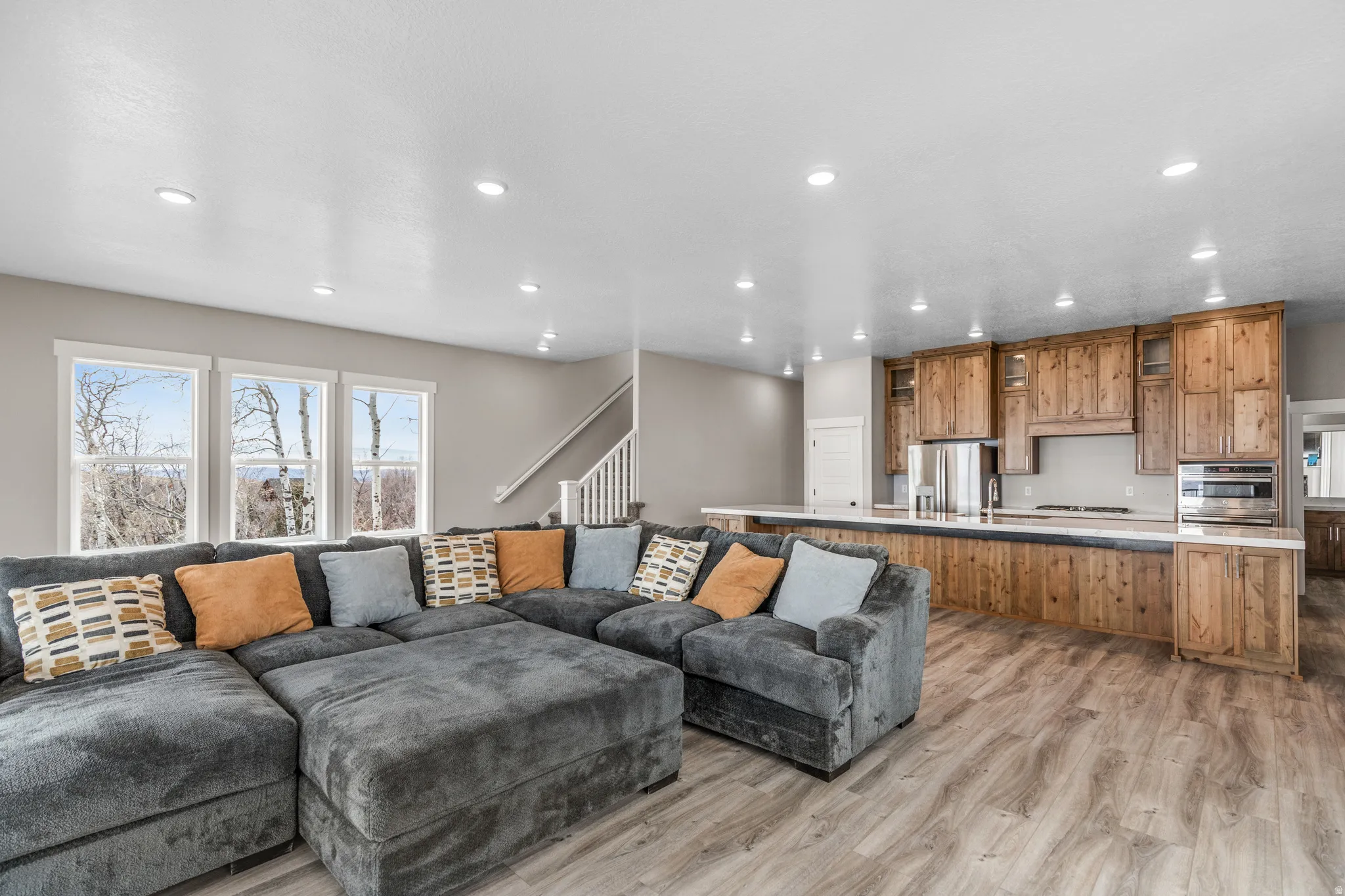 Living room featuring light wood-style flooring, stairs, and recessed lighting