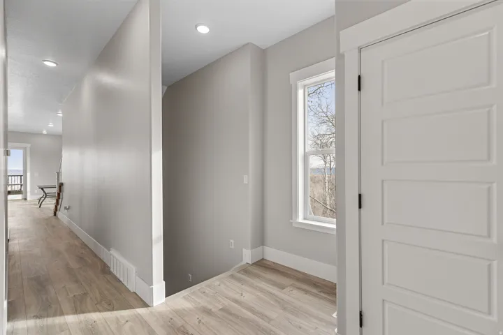 Hall with light wood-type flooring, recessed lighting, and an upstairs landing