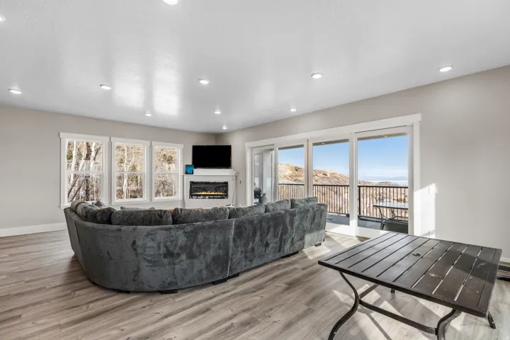 Living room featuring a glass covered fireplace, light wood finished floors, and recessed lighting