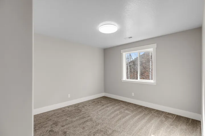 Empty room featuring light colored carpet and a textured ceiling