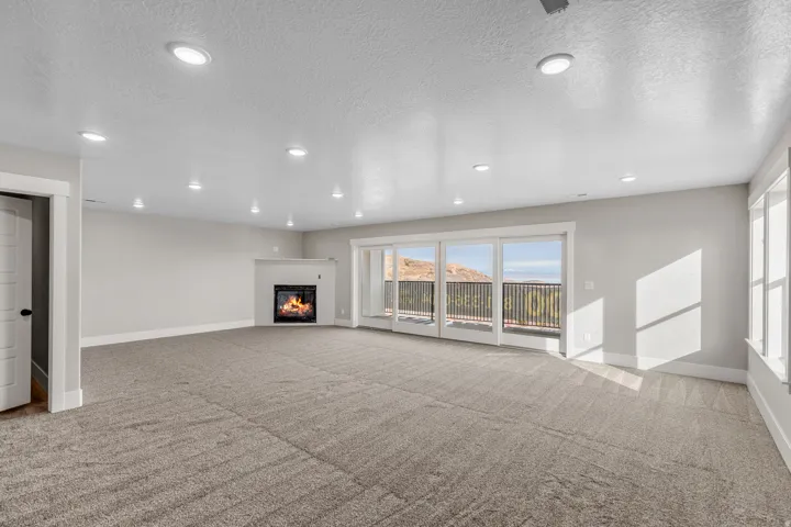 Unfurnished living room with recessed lighting, a textured ceiling, a glass covered fireplace, and light colored carpet