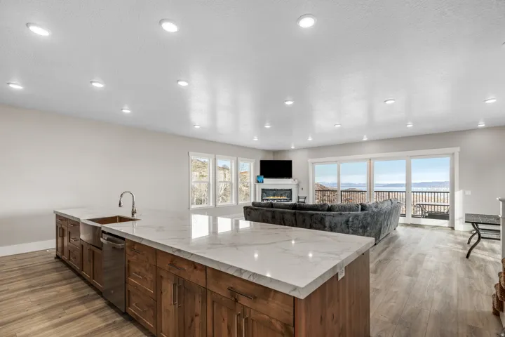 Kitchen featuring light wood-type flooring, light stone counters, a glass covered fireplace, open floor plan, and recessed lighting