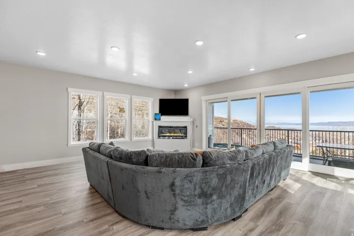 Living room with a glass covered fireplace, plenty of natural light, light wood finished floors, and recessed lighting