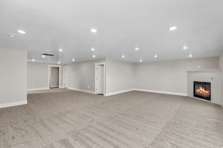 Unfurnished living room with a glass covered fireplace, recessed lighting, and light colored carpet