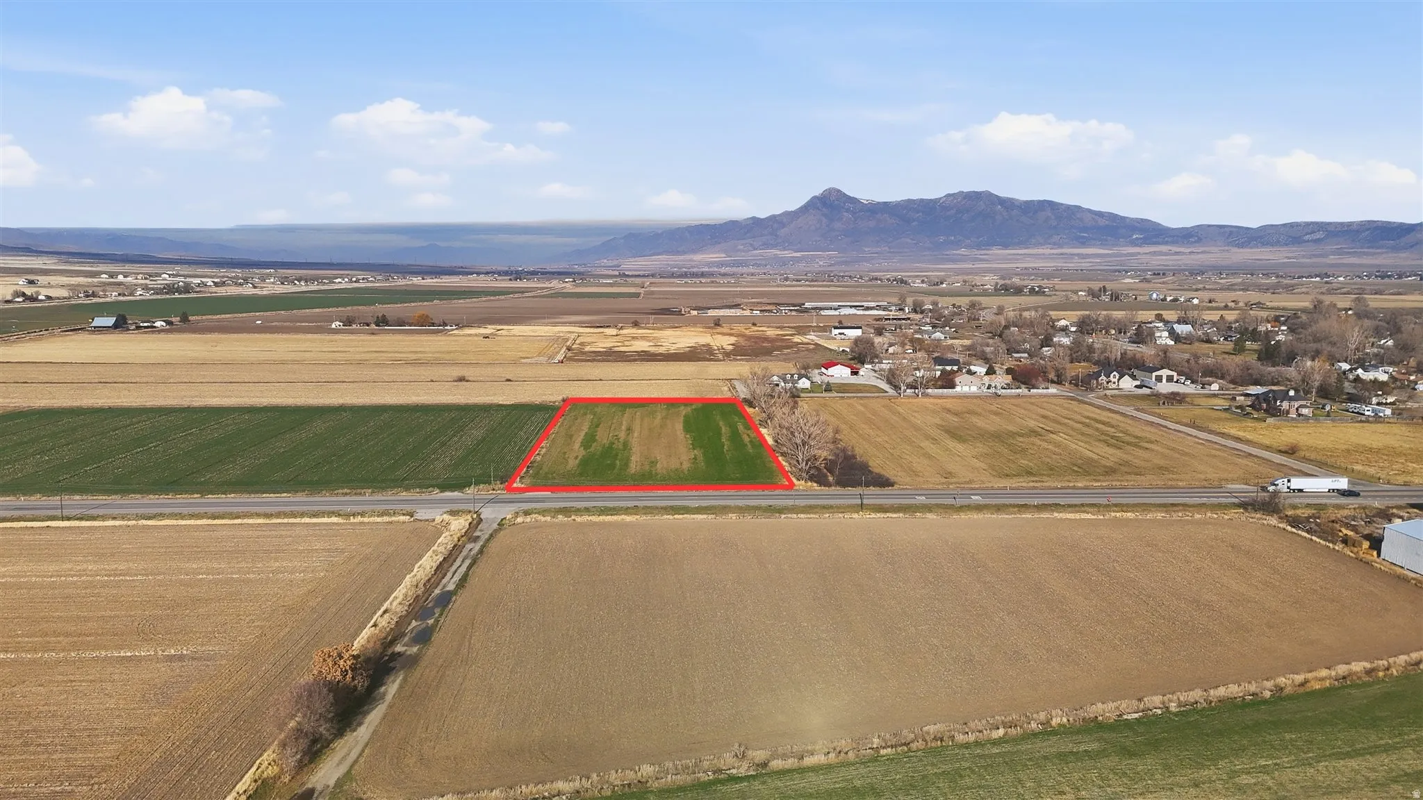 Aerial view of sparsely populated area featuring property boundaries highlighted, abundant farmland, and a mountain backdrop