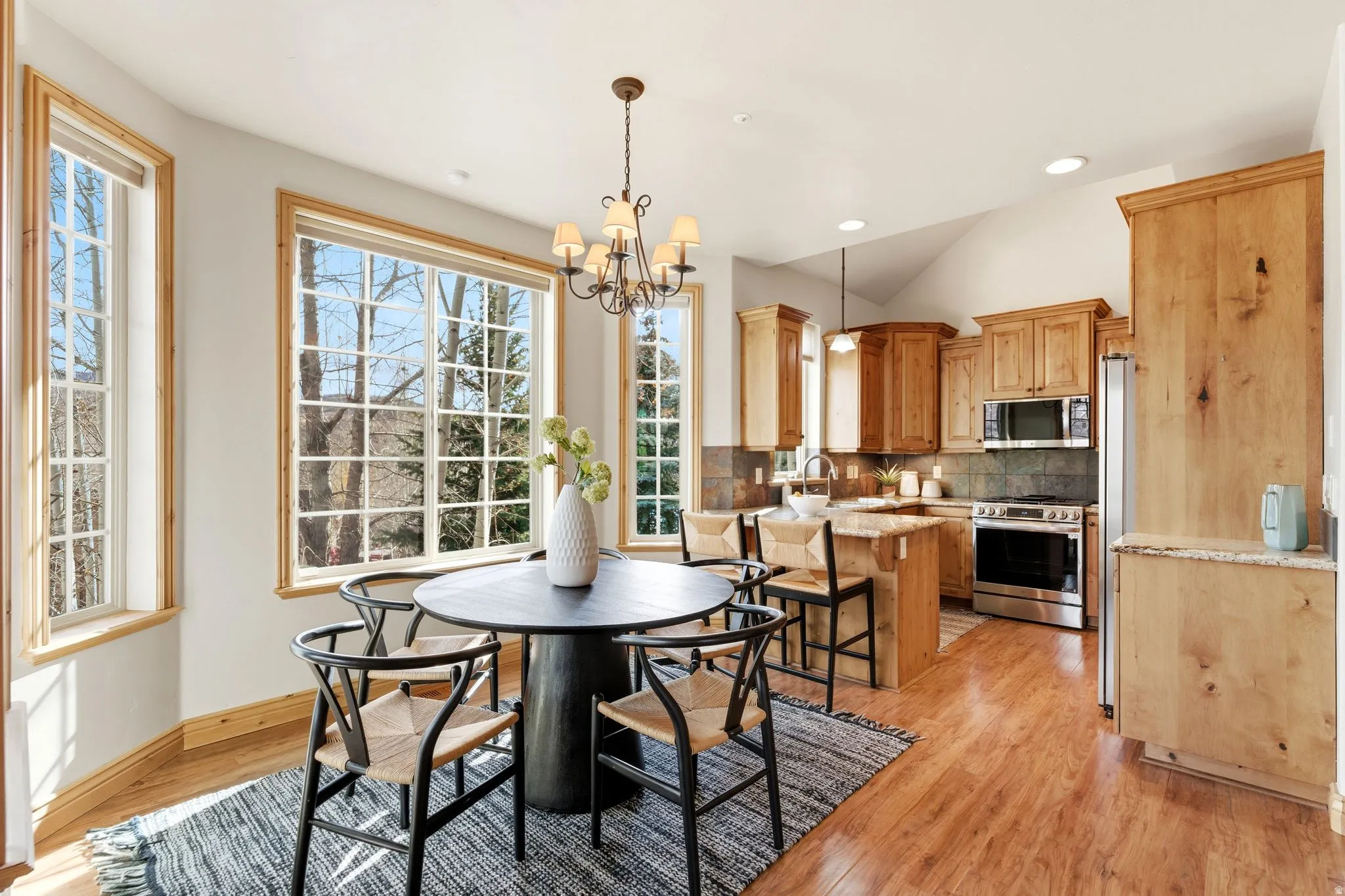 Dining room with a chandelier, light wood-type flooring, recessed lighting, and vaulted ceiling