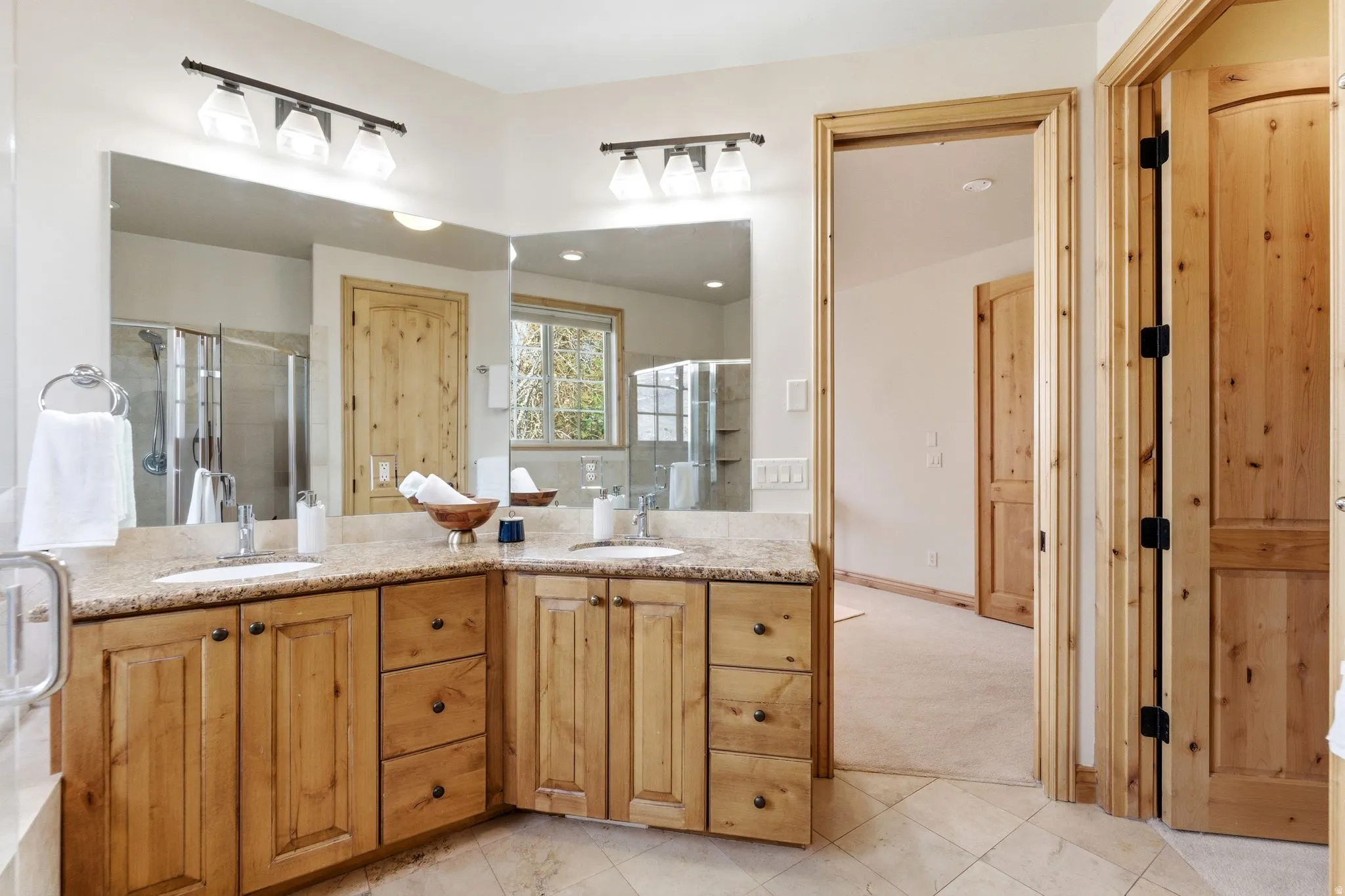 Bathroom with double vanity, a stall shower, and light carpet