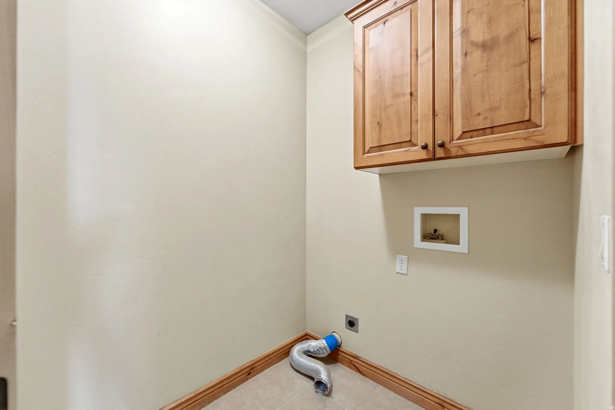 Laundry room featuring hookup for an electric dryer, cabinet space, hookup for a washing machine, and tile patterned flooring