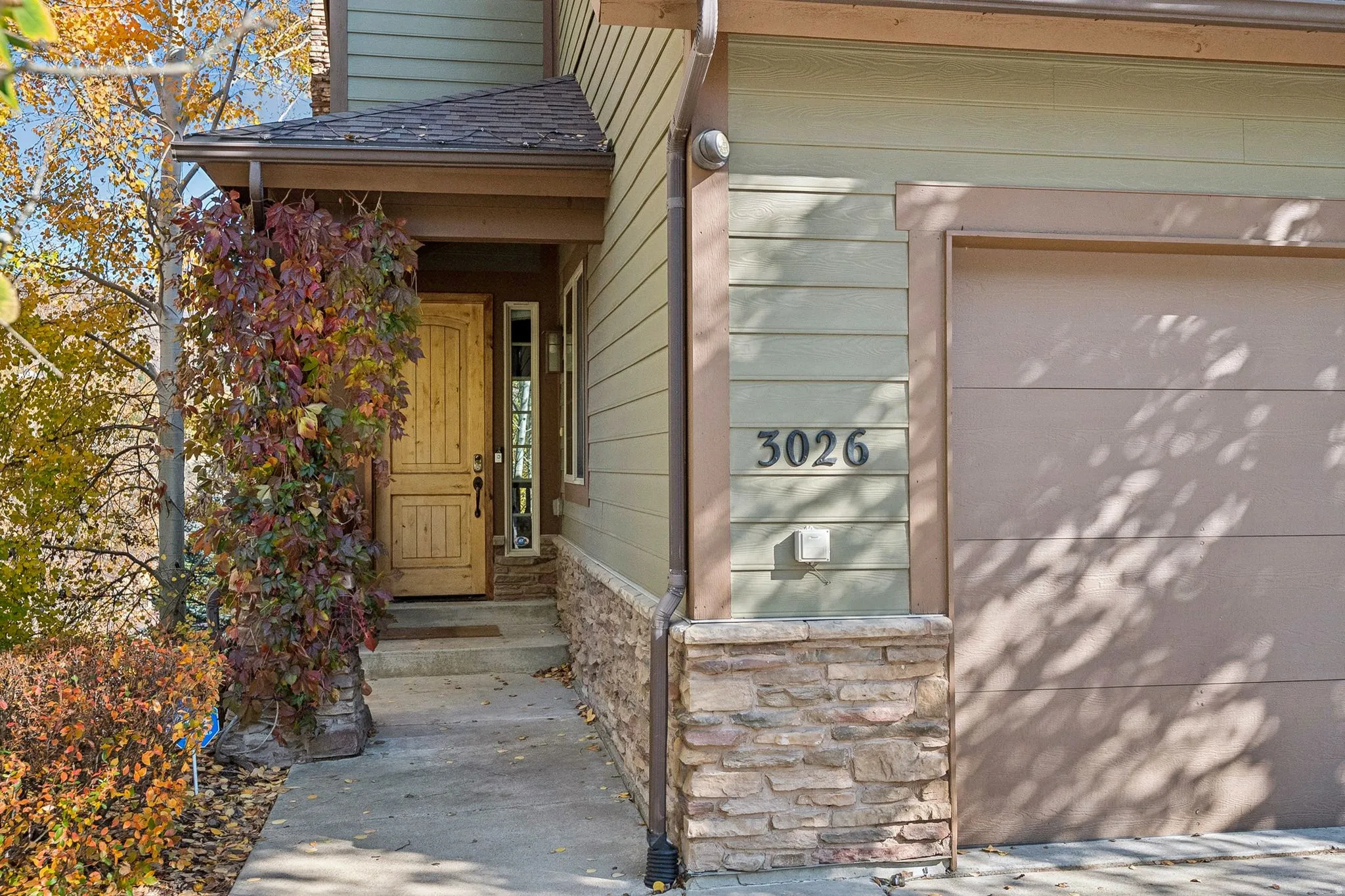 Property entrance featuring a garage, stone siding, and a shingled roof