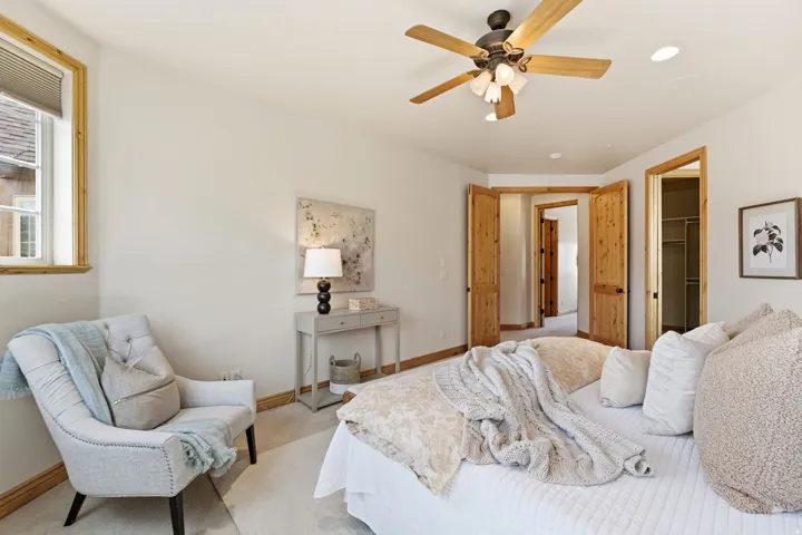 Bedroom with a spacious closet, ceiling fan, and carpet floors