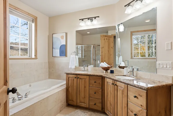 Bathroom featuring double vanity, healthy amount of natural light, a shower stall, and a garden tub