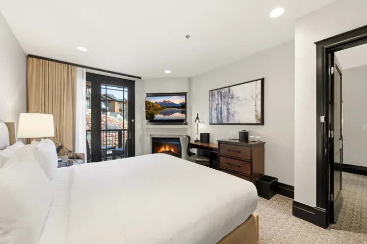 Bedroom with access to exterior, a glass covered fireplace, recessed lighting, and light colored carpet