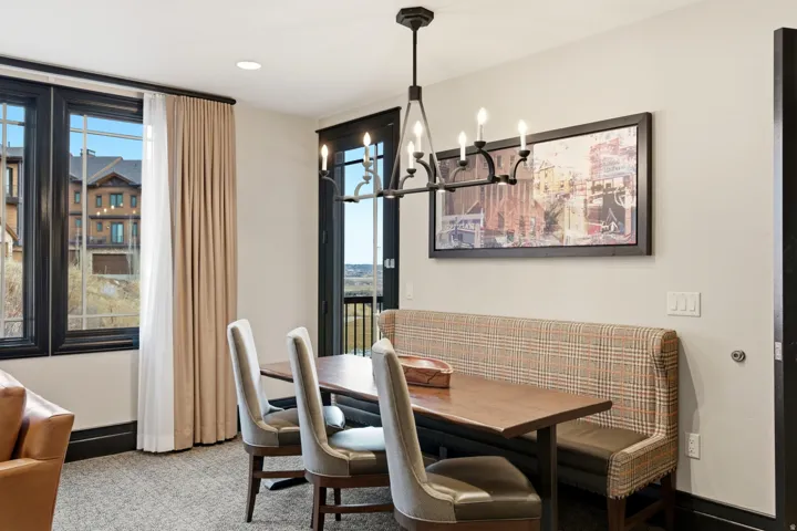 Carpeted dining area with a chandelier and recessed lighting