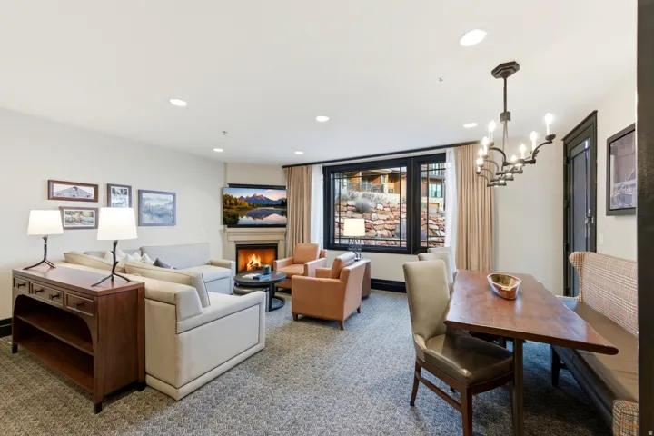 Carpeted living room featuring a lit fireplace, a chandelier, and recessed lighting