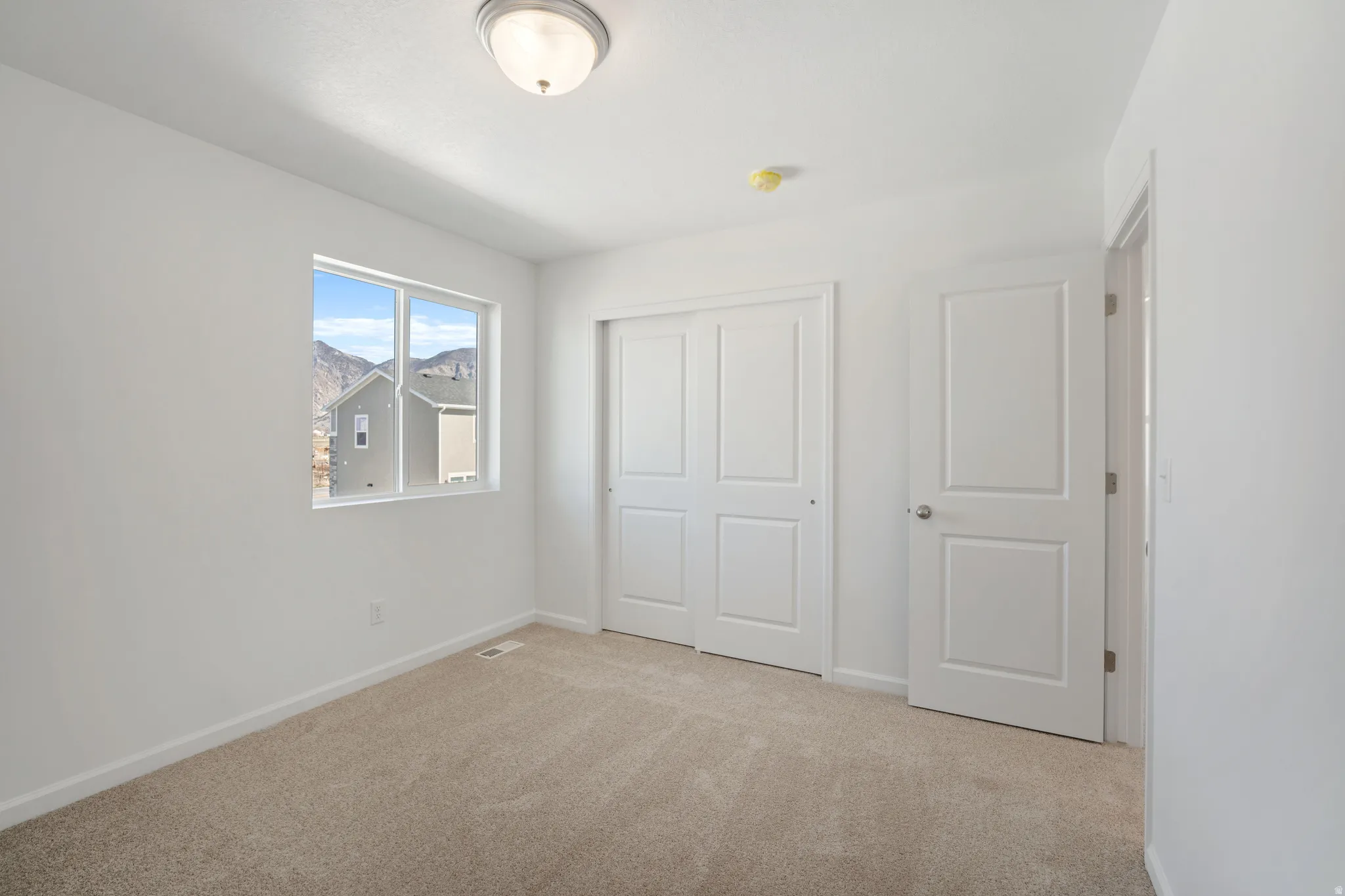 Unfurnished bedroom featuring light colored carpet and a closet