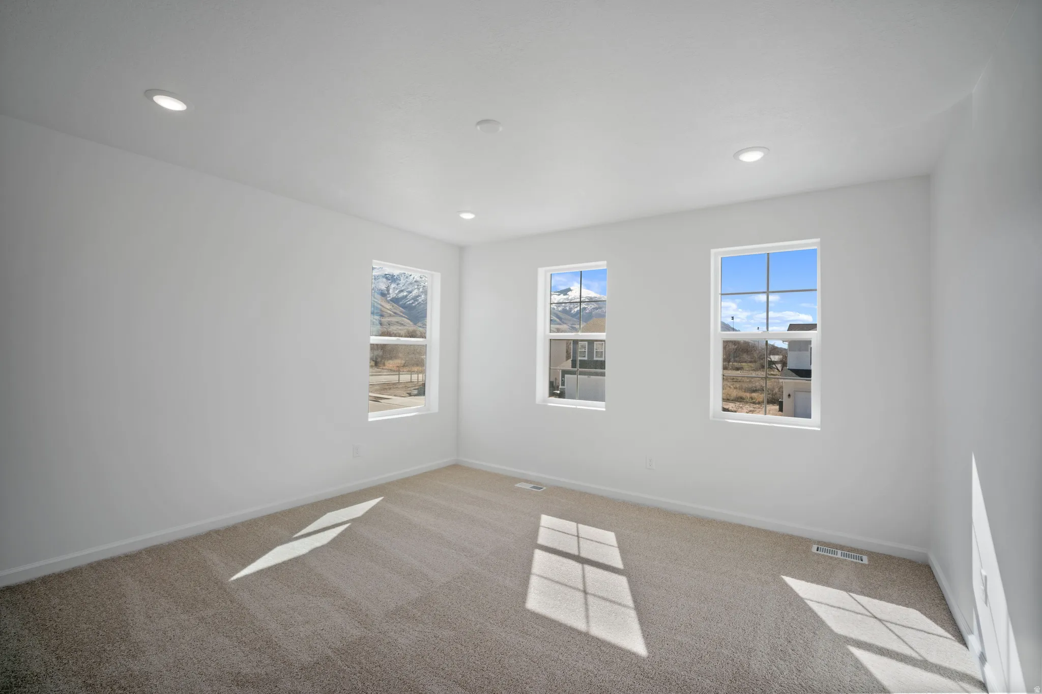 Empty room with light carpet and recessed lighting