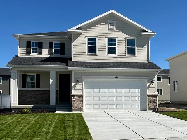 View of front facade featuring covered porch, stone siding, an attached garage, and concrete driveway