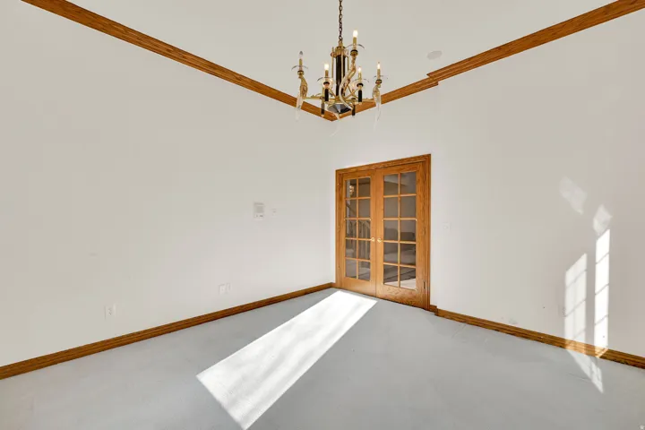 Carpeted empty room with a chandelier and ornamental molding