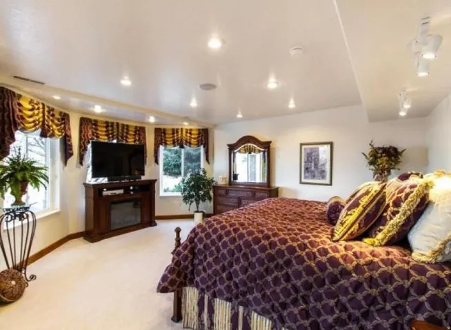 Bedroom featuring light colored carpet and a fireplace