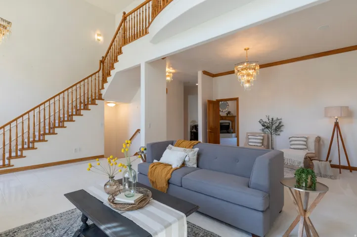 Living room with a chandelier, stairs, and a high ceiling