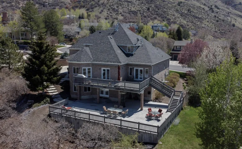 Back of property featuring a fenced backyard, roof with shingles, a deck, and a patio area