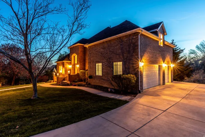 View of property exterior with a yard, a garage, concrete driveway, and brick siding