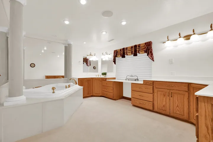 Bathroom featuring vanity, a bath, light carpet, and recessed lighting
