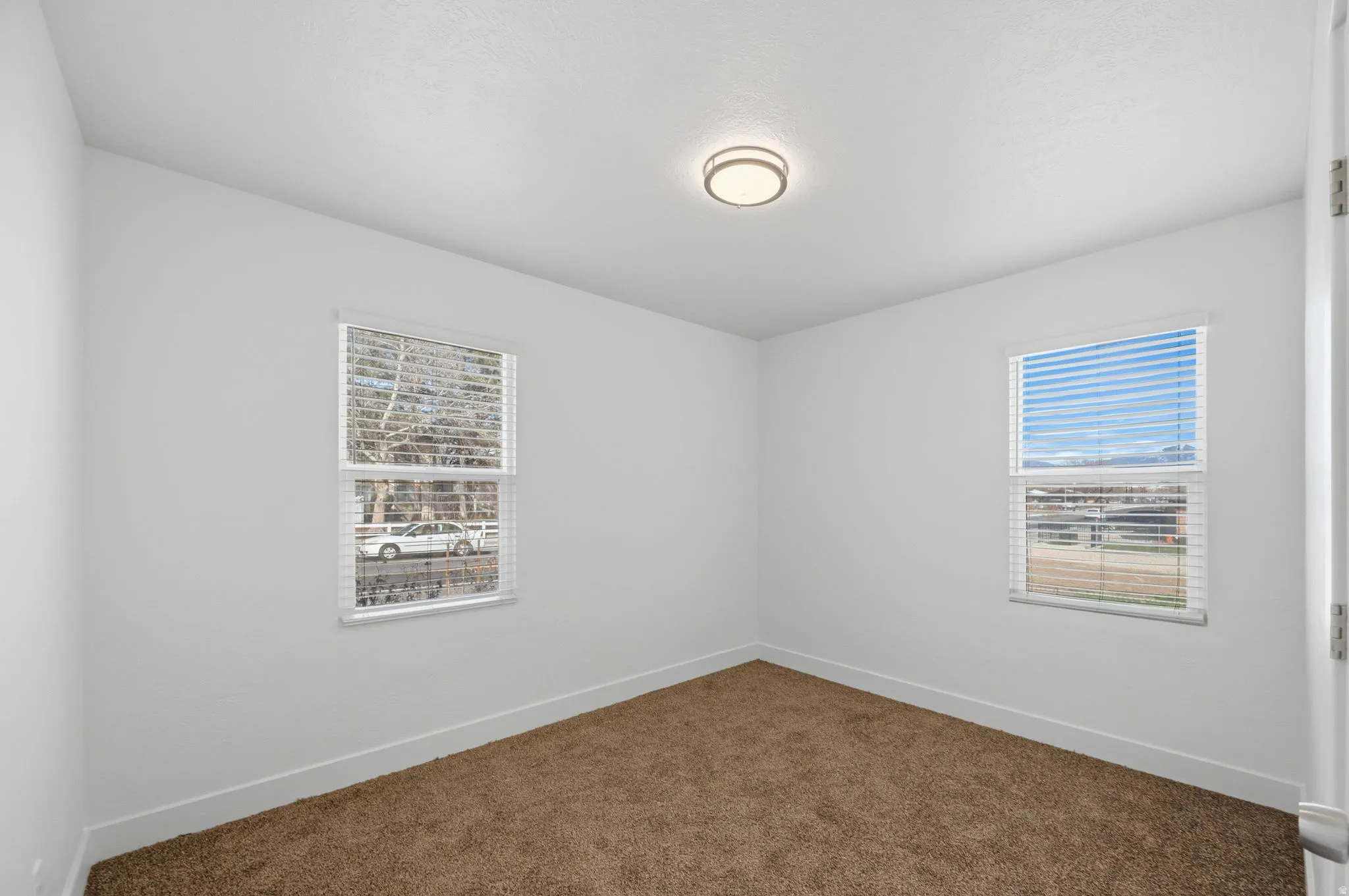 Empty room with dark colored carpet and healthy amount of natural light