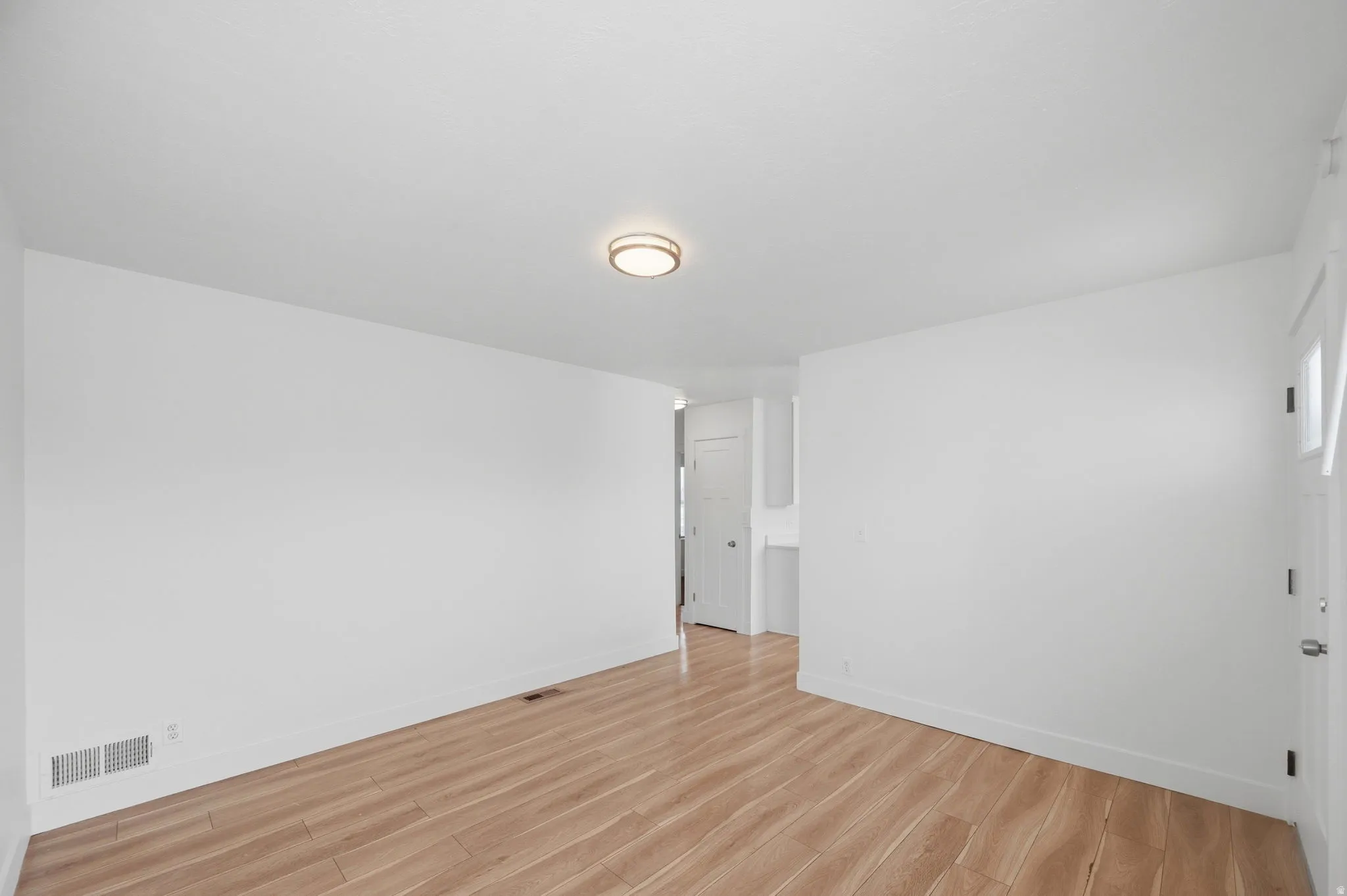 Spare room featuring light wood-type flooring and baseboards
