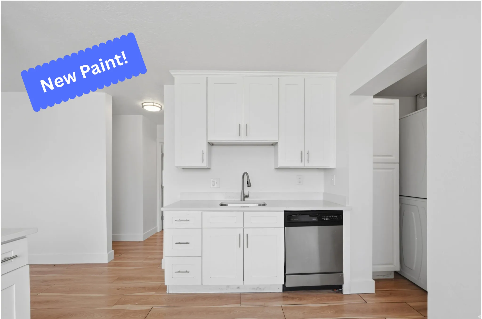 Kitchen featuring dishwasher, white cabinets, light wood-style floors, light stone counters, and washer / clothes dryer