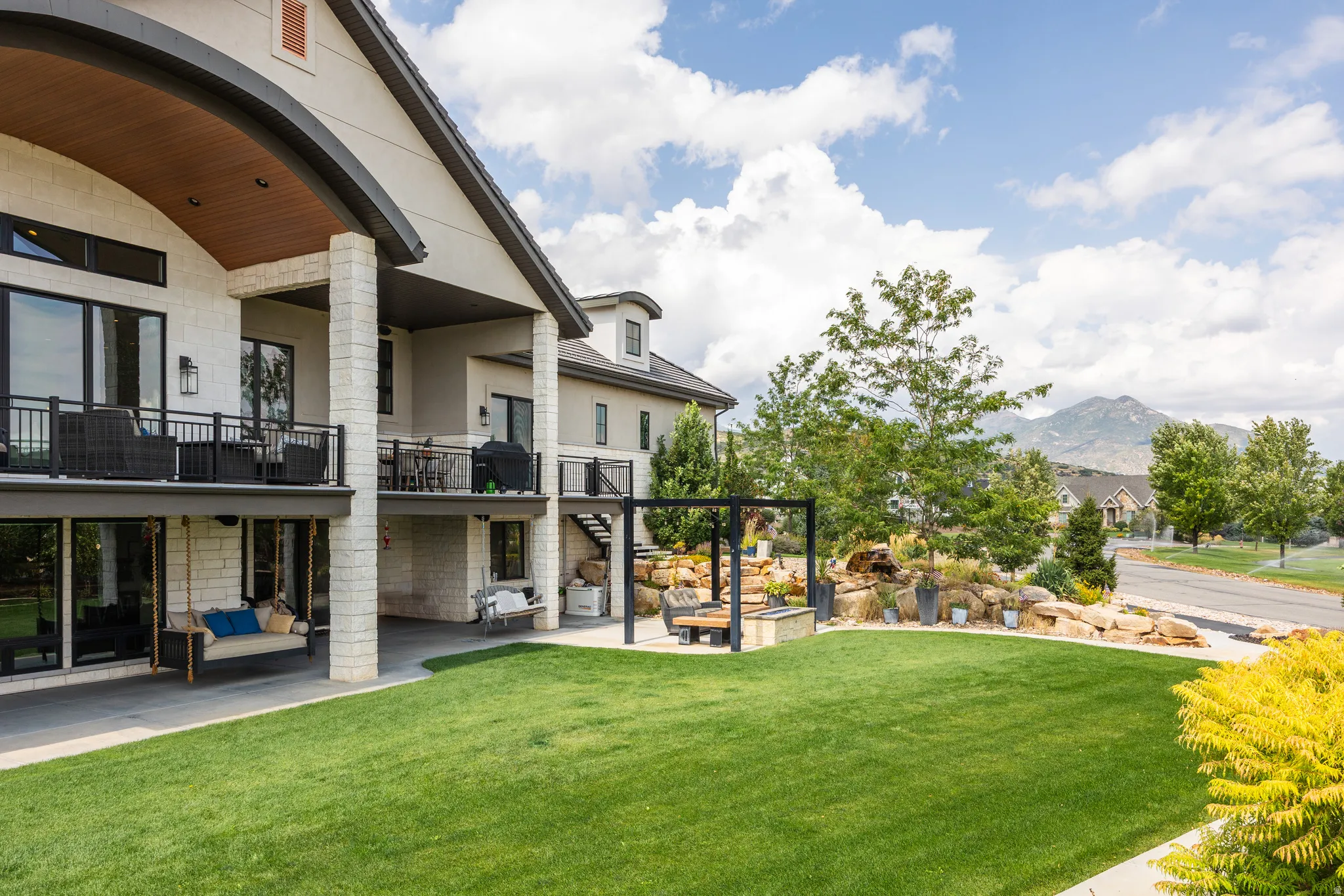 View of green lawn with stairway, a balcony, a patio, and a mountain view
