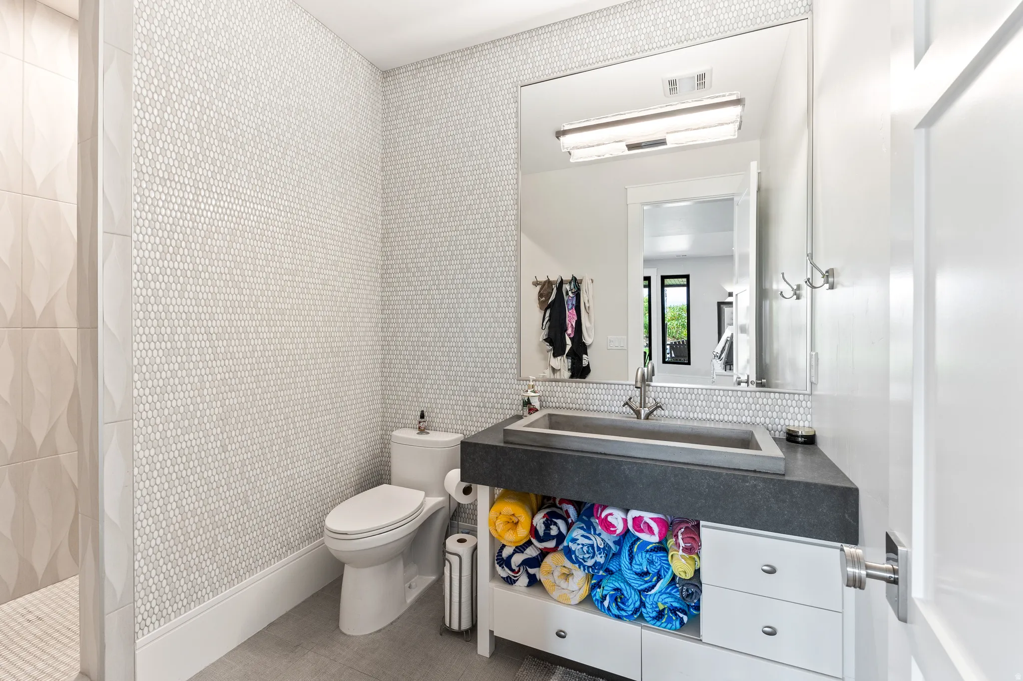Full bathroom with a tile shower, wallpapered walls, and vanity