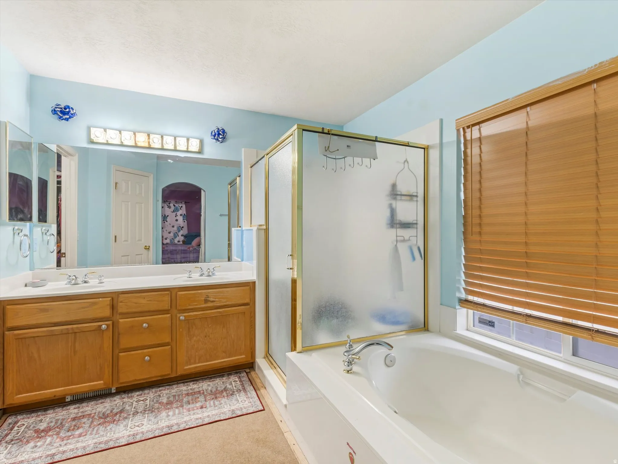 Ensuite bathroom featuring a garden tub, a stall shower, and double vanity