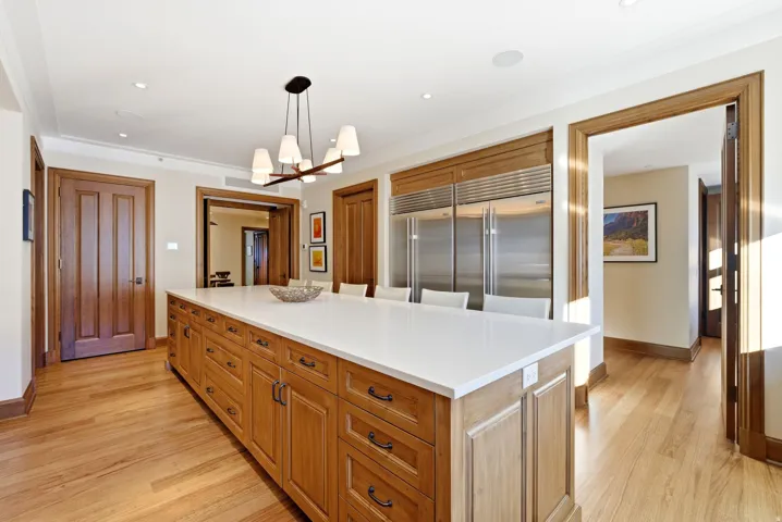 Kitchen with brown cabinetry, decorative light fixtures, light wood-type flooring, a center island, and built in fridge