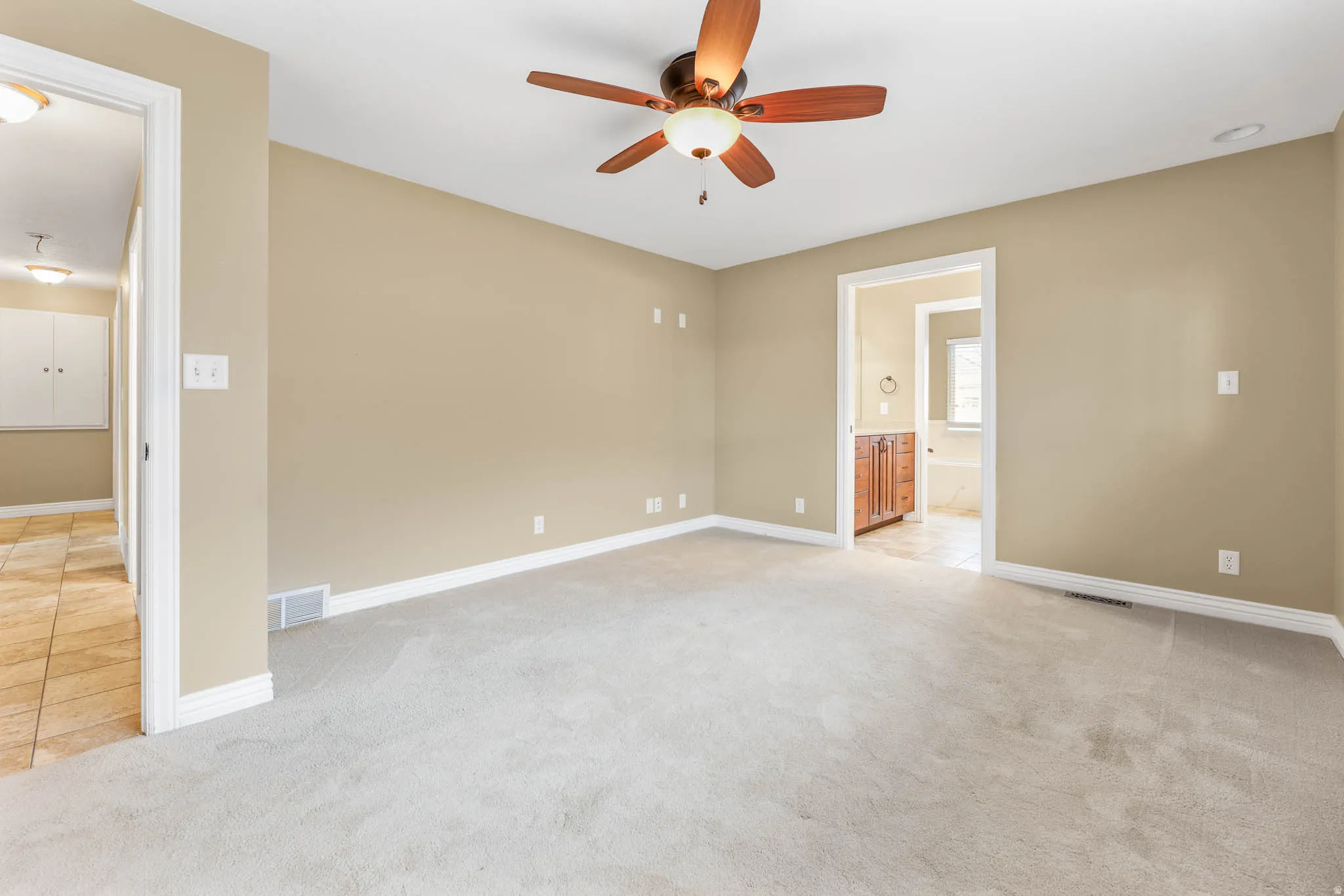 Unfurnished room featuring light colored carpet and a ceiling fan