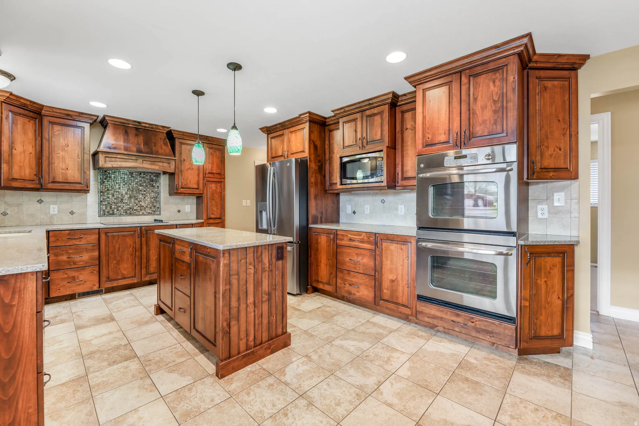 Kitchen with stainless steel appliances, backsplash, brown cabinets, a center island, and recessed lighting