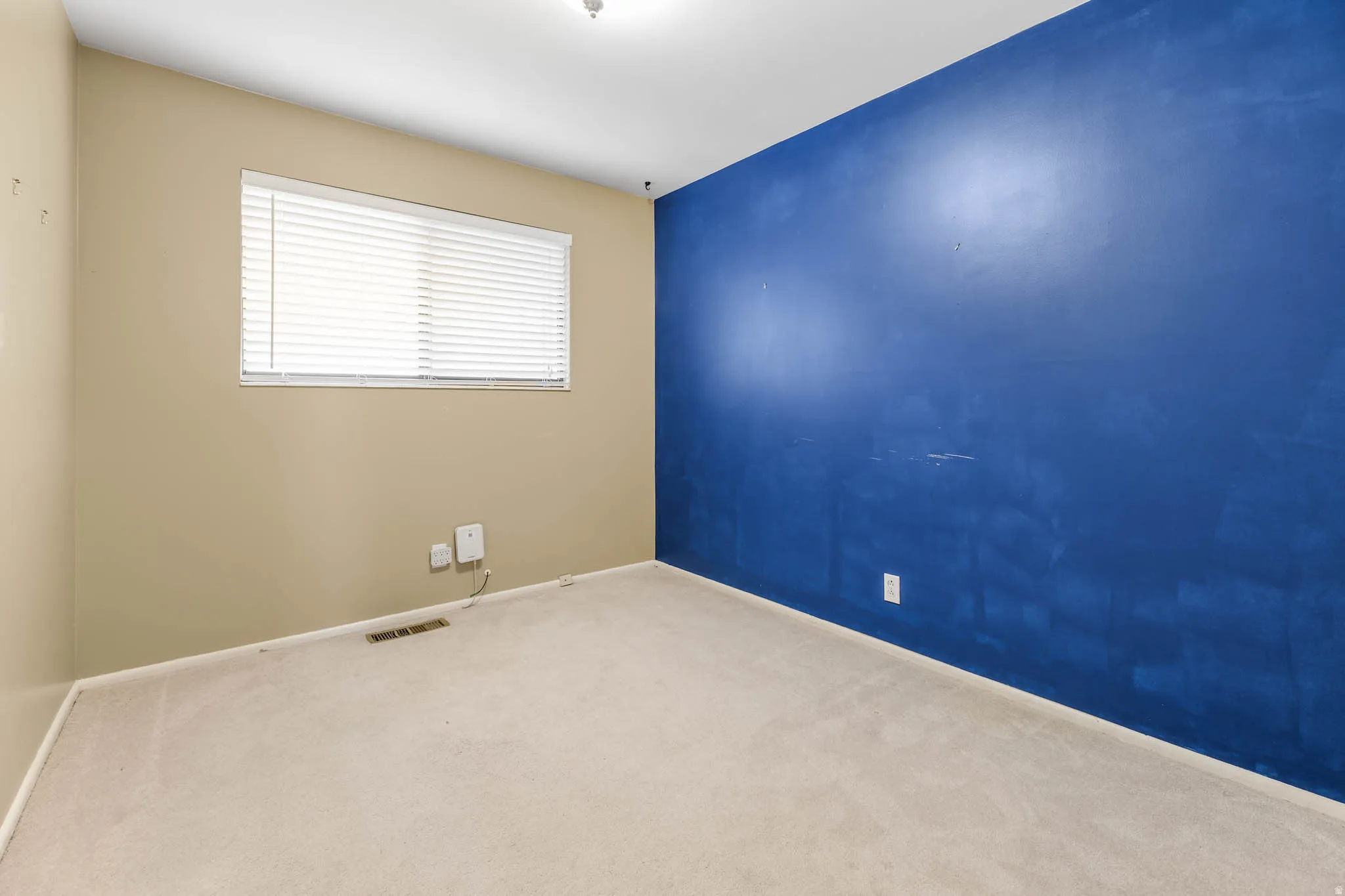 Carpeted spare room featuring baseboards