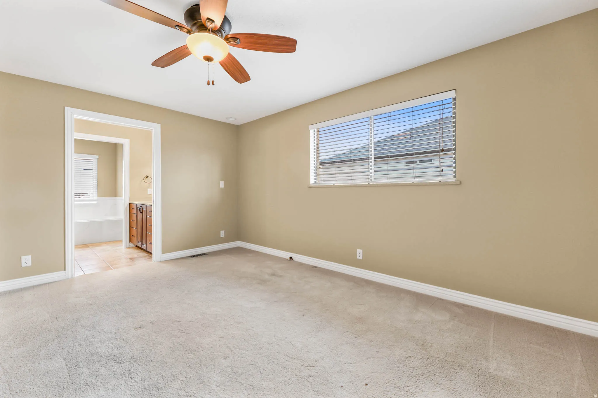 Empty room featuring light carpet and a ceiling fan